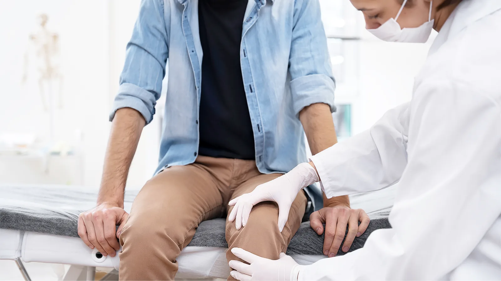 Clinician examining the knee of a seated patient
