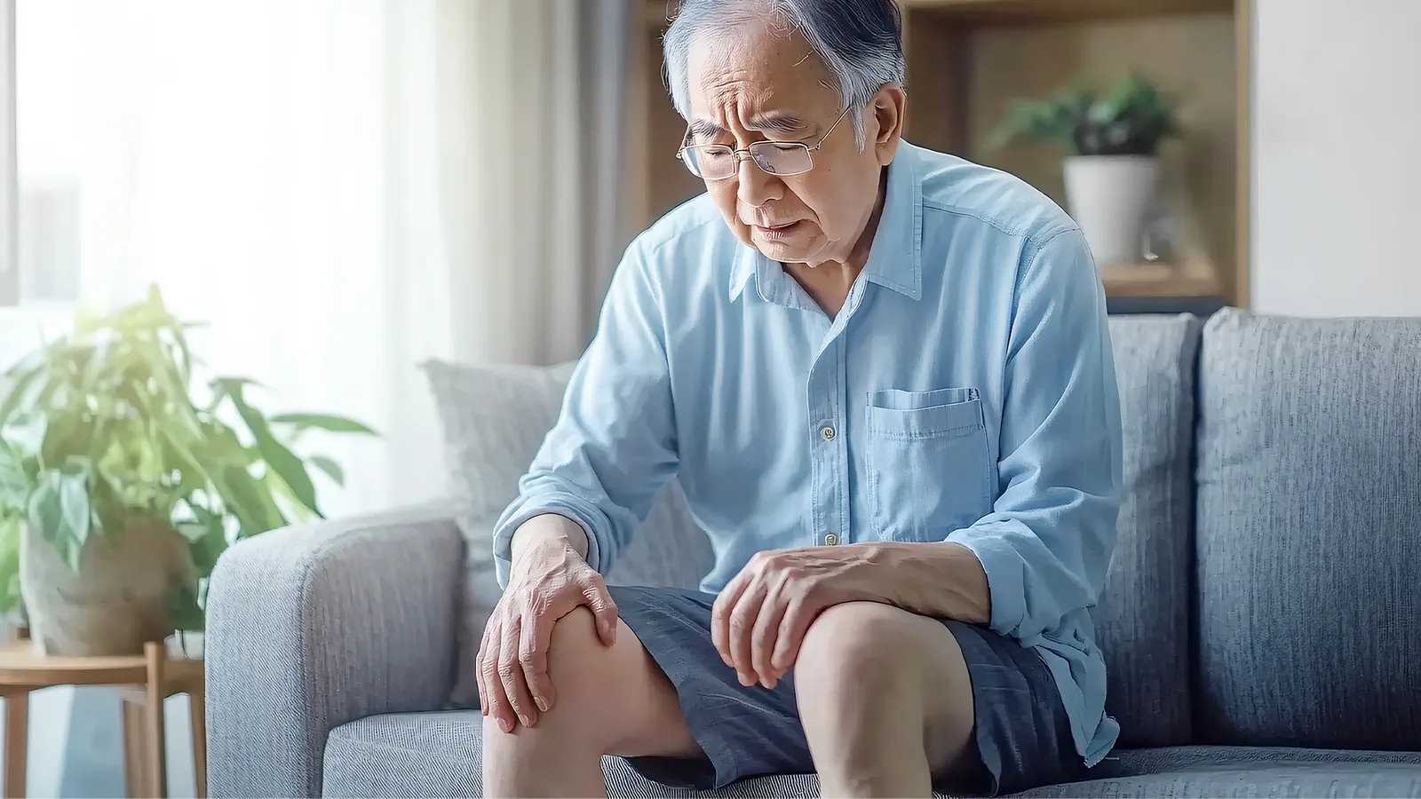 رجل كبير في السنّ يجلس على أريكة واضعاً يده على ركبته