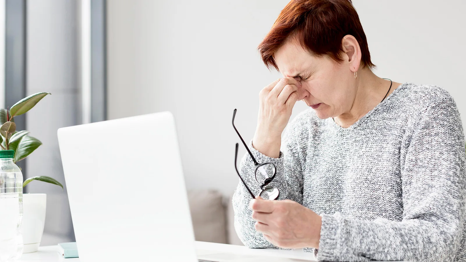شخص أمام حاسوب محمول يرفع نظارته ويفرك عينيه