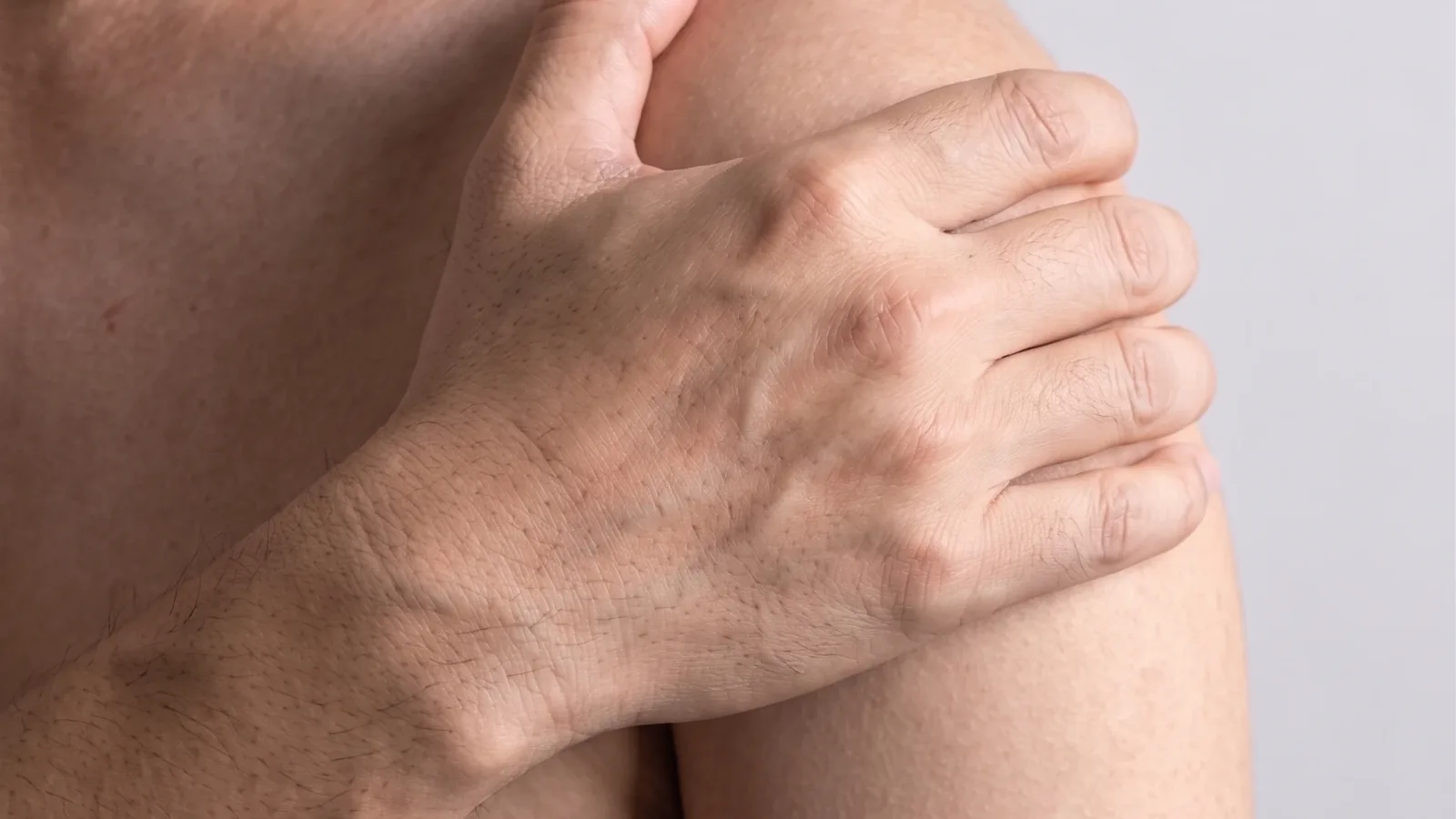 Bare shoulder with a hand reaching across to it