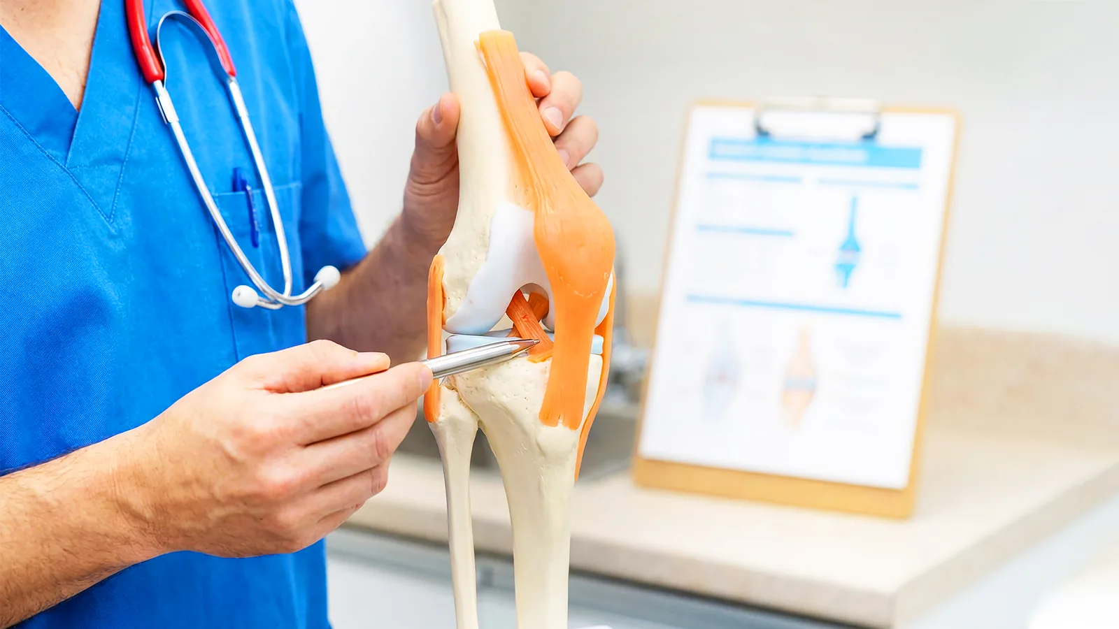 Nurse pointing at a knee model beside an explanatory chart