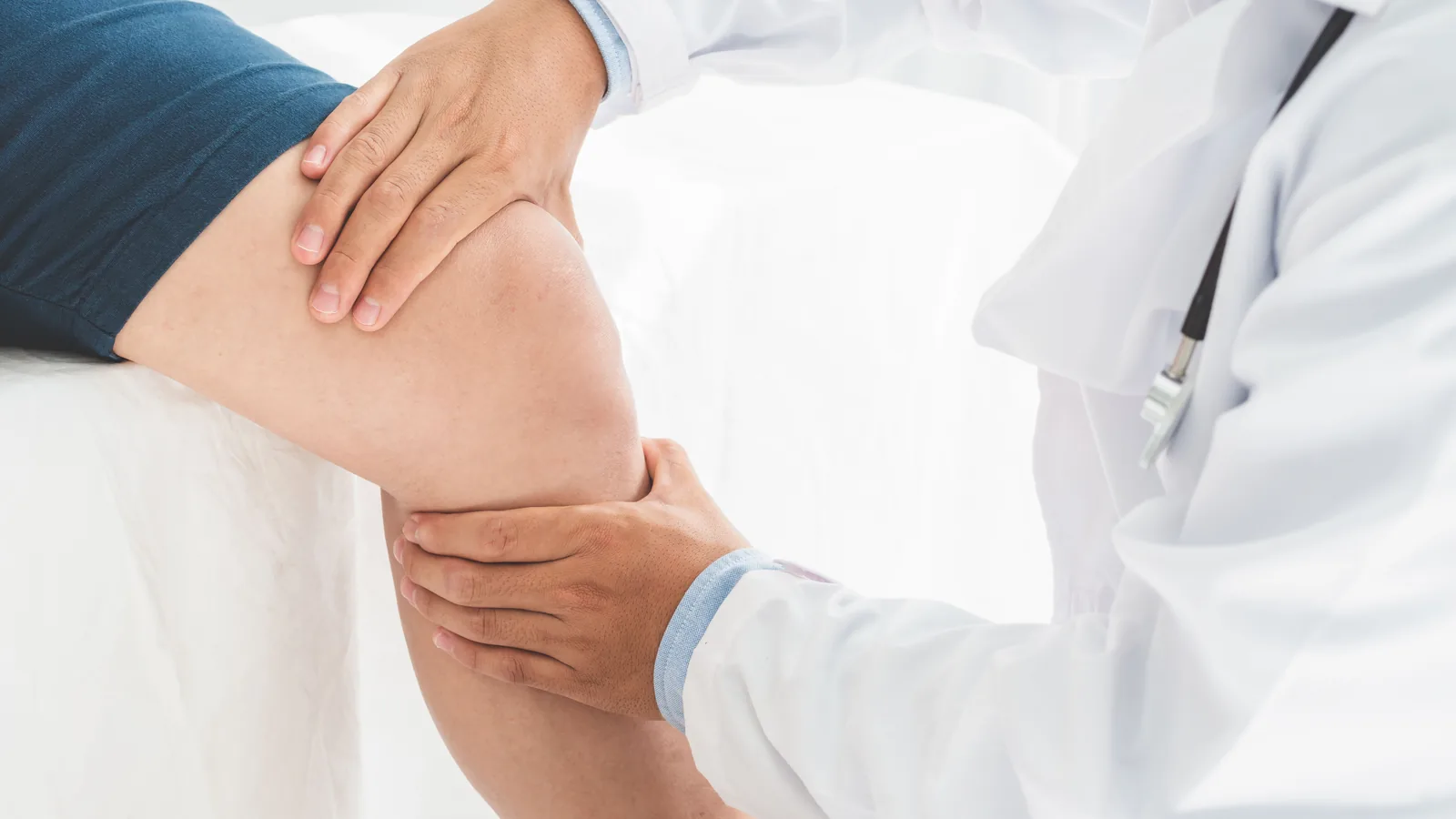 Clinician's hands assessing a knee at the joint line