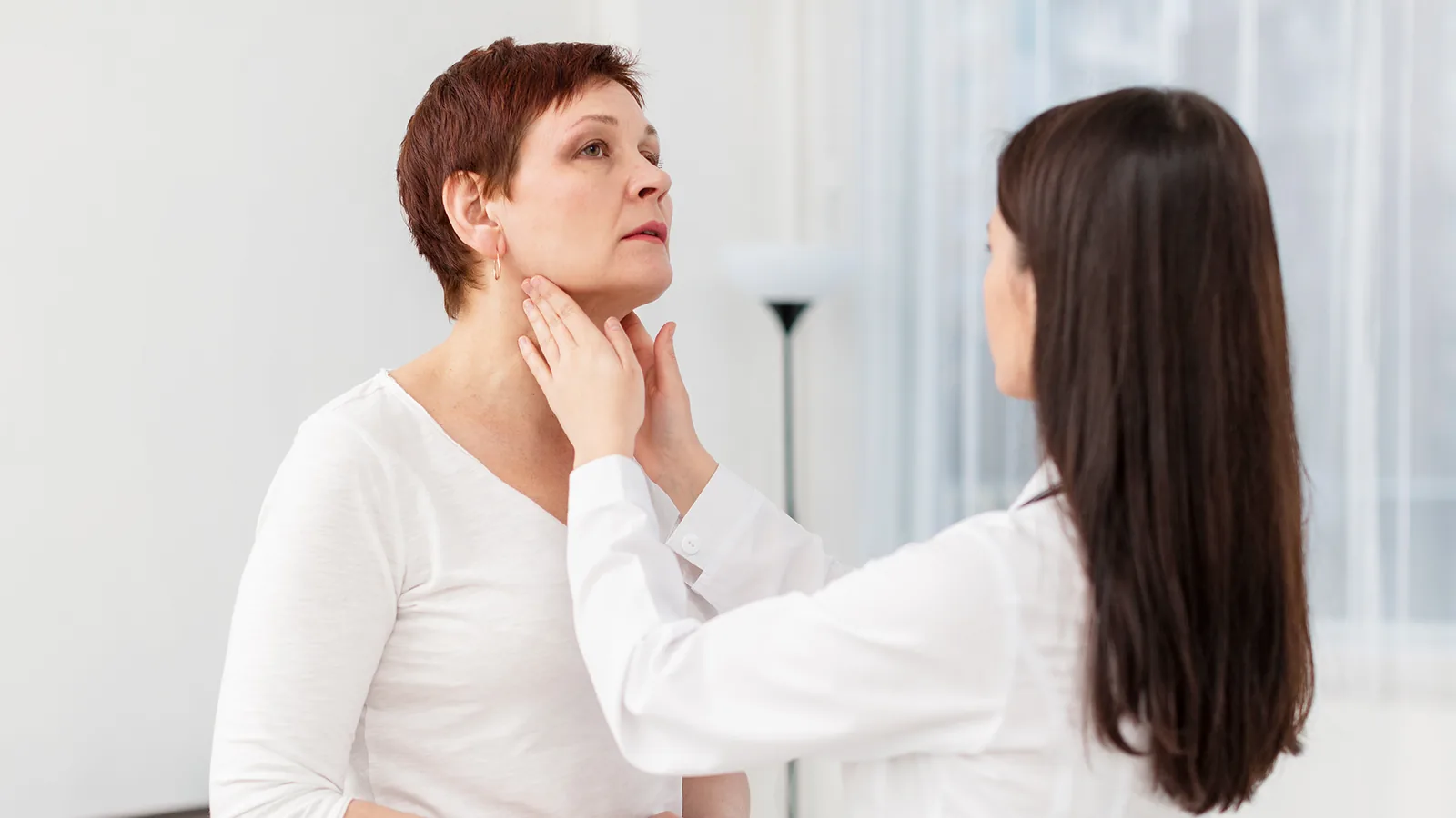 Older woman being examined by a clinician in a bright room