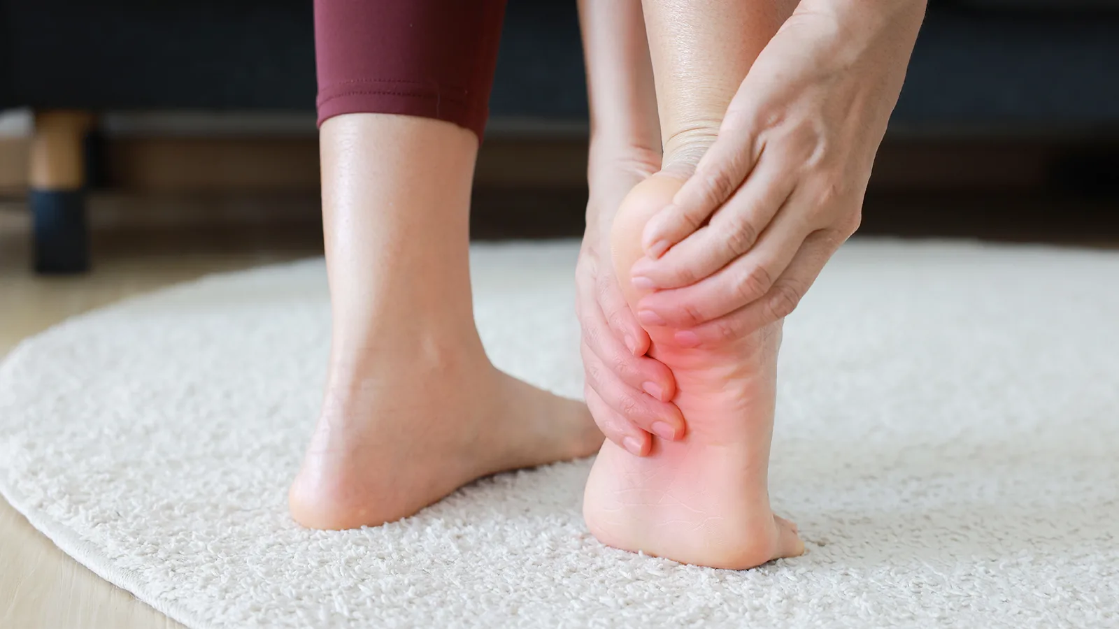 Person standing on a rug holding one heel