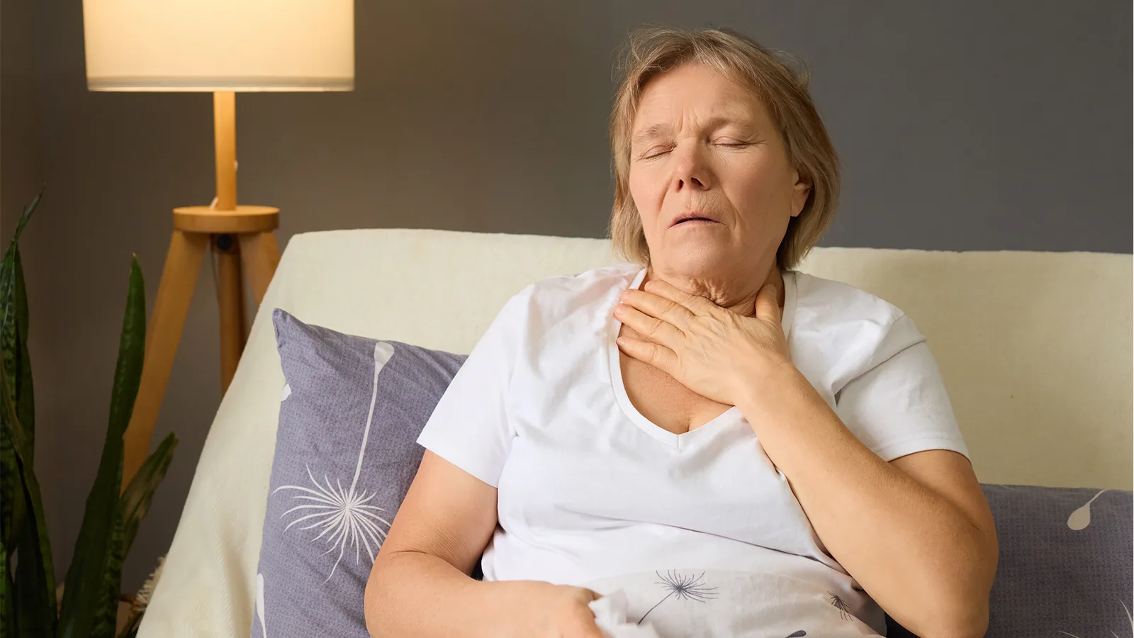 Older woman awake in bed at night with the lamp on