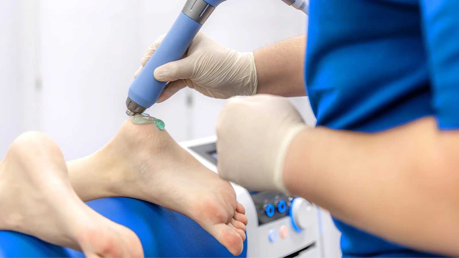 Gloved clinician treating the back of a heel with a handheld device